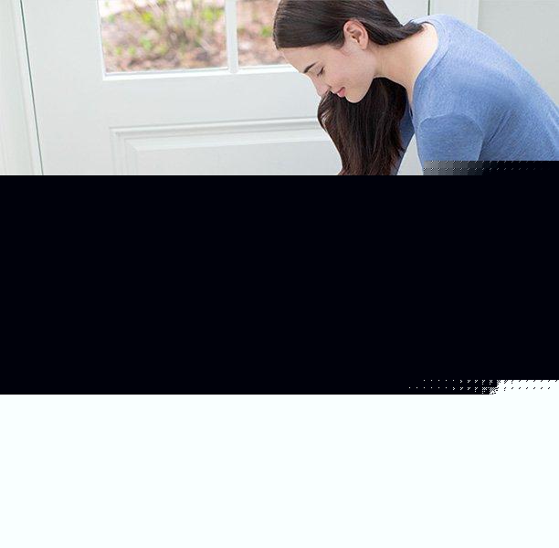 Woman using her Cleanslate portable spot cleaner to clean muddy paw prints out of a white area rug